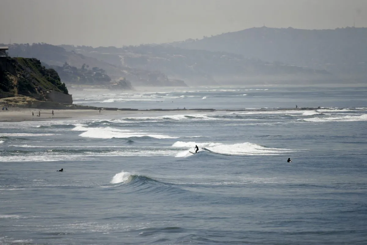 In this April, 2008, file photo, people swim and surf in the Pacific Ocean at Cardiff State Beach near Solana Beach, Calif. (Lenny Ignelzi/AP Photo)
