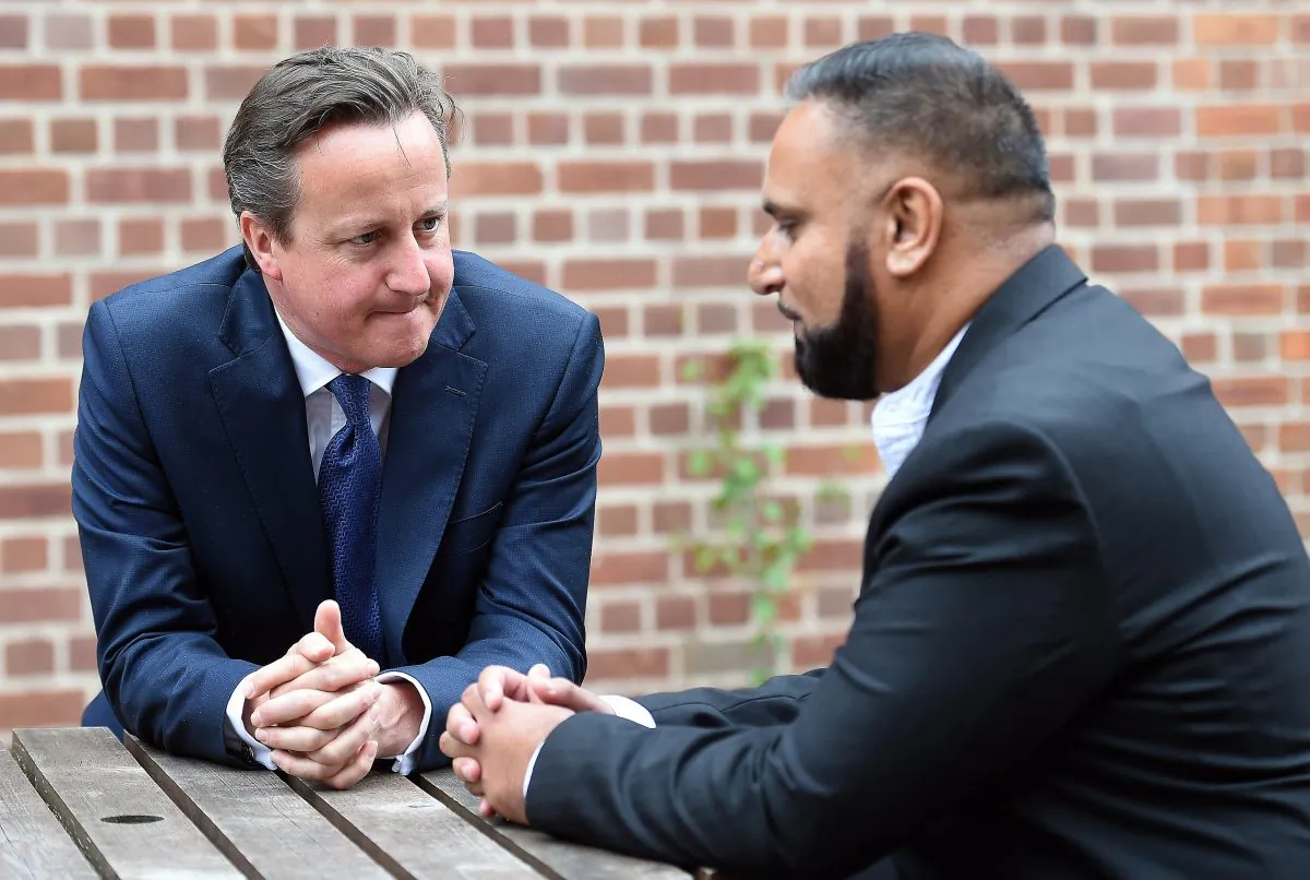 British Prime Minister David Cameron, speaks with Abdullah Rehman, a local resident whose family Cameron once stayed overnight with in 2007, in Birmingham, central England, on July 20, 2015, before delivering a speech at Ninestiles Academy. (Paul Ellis/AFP/Getty Images)