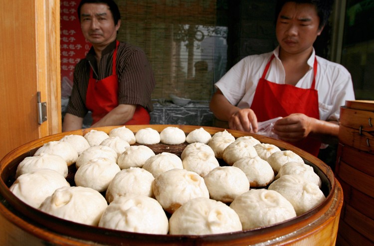 Chinese vendors prepare steaming pork buns on sale at a sidewalk stall in Beijing, file photo. Wheat more so than rice is the staple starch in Beijing and the North because of the colder climate. So popular dishes in the region are made from wheat flour such as pasta, pancakes, and steamed buns.  (Teh Eng Koon/AFP/Getty Images)