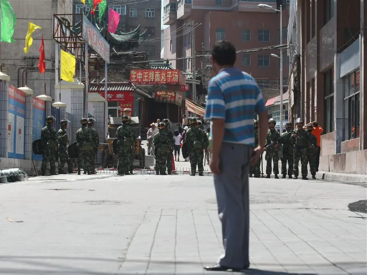 A Uyghur man looks at Chinese policemen blocking a street on July 9, 2009 in Urumqi, the capital of Xinjiang Uyghur autonomous region, China. (Guang Niu/Getty Images)