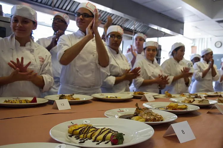 High-school seniors stand in front of dishes they prepared for a culinary competition held by Careers through Culinary Arts Program on March 27, and listen to feedback from the judges. (Benjamin Chasteen/The Epoch Times)