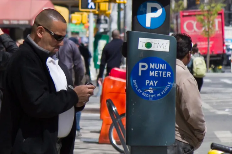A man pays for parking at a MUNI parking meter in Midtown Manhattan on April 8. (Benjamin Chasteen/The Epoch Times)