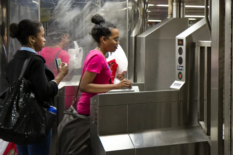 Commuters using their MTA Metro cards at the turnstile of the Harold Square subway station on May 23. (Benjamin Chasteen/The Epoch Times)
