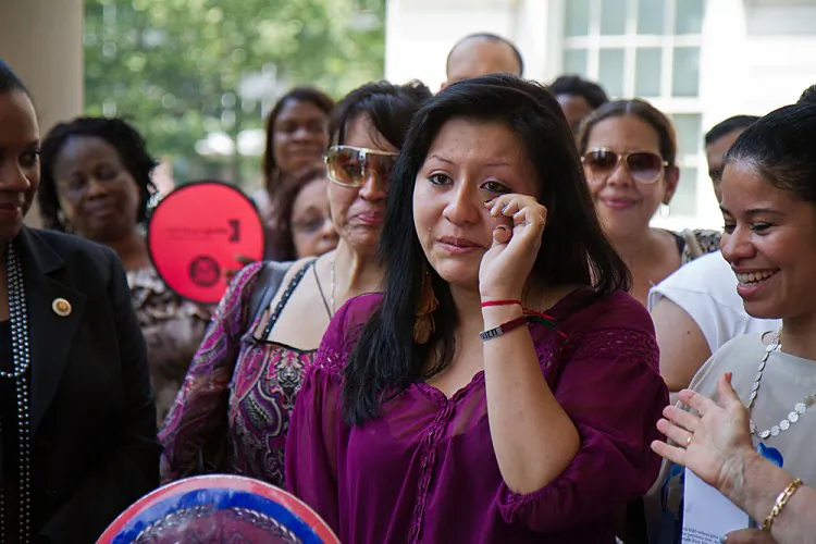 Jacqueline Rios cries as she recalls how the nonprofit suicide prevention program for Hispanic teens saved her life. Council member Julissa Ferreras is standing to Rios's left, and Beatriz Coronel, the suicide prevention program coordinator, stands on her right on the New York City Hall steps on June 20. (Benjamin Chasteen/The Epoch Times)