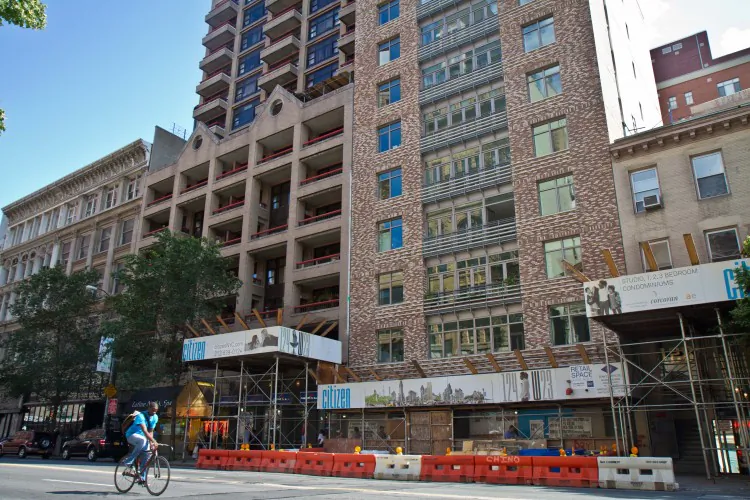 A cyclist rides past Citizen, a new condominium building on 124 W. 23rd St., in Manhattan on July 2. (Benjamin Chasteen/The Epoch Times)