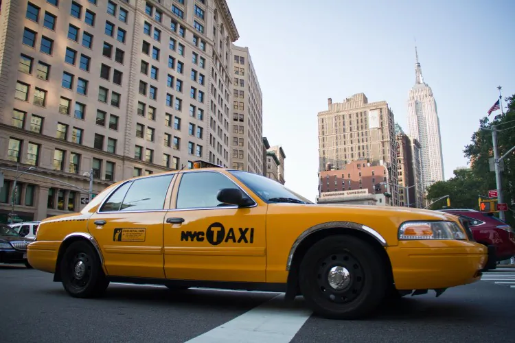 A taxi drives across 23rd Street in the Flatiron District of Manhattan on July 12 with the Empire State Building in the background. (Benjamin Chasteen/The Epoch Times)