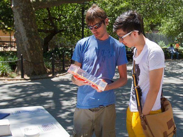 Jackson holds a display of dead tapeworms as he explains to a passerby how a $1 donation would help de-worm 67 infected children in Haiti. (Benjamin Chasteen/The Epoch Times)