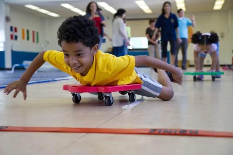 Five-year-old Caleb Rodriguez races to the finish line on a scooter board at the New York Institute for Special Education Olympics for preschoolers on Aug. 2, in Bronx, N.Y. (Benjamin Chasteen/The Epoch Times)