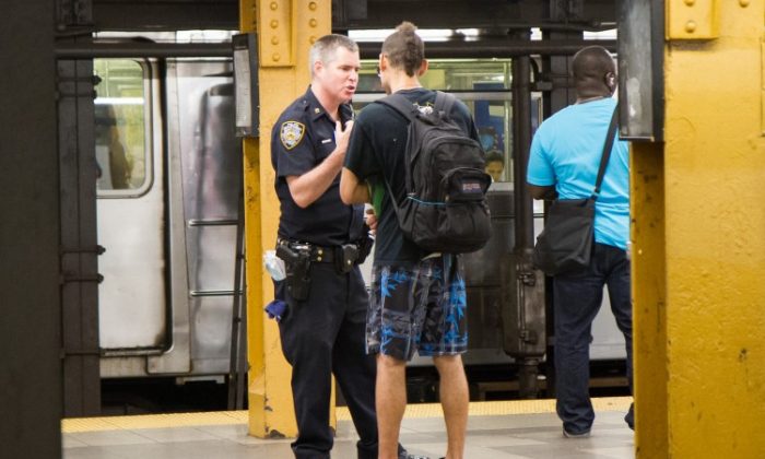 A young man is questioned before being frisked by a police officer at the Penn Station subway platform in Manhattan on Aug. 7. (Benjamin Chasteen/The Epoch Times)
