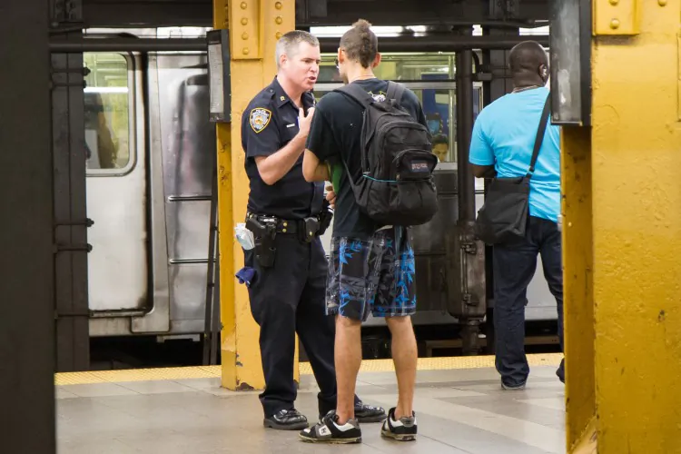 A young man is questioned before being frisked by a police officer at the Penn Station subway platform in Manhattan on Aug. 7. (Benjamin Chasteen/The Epoch Times)
