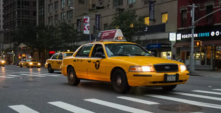 A New York City taxi with the new logo on the side of the car drives up Sixth Avenue in Midtown Manhattan on Sept. 3. (Benjamin Chasteen/The Epoch Times)