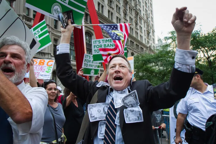 An Occupy Wall Street protestor holds up signs in Zuccotti Park, Manhattan, on Sept. 17. (Benjamin Chasteen/The Epoch Times)