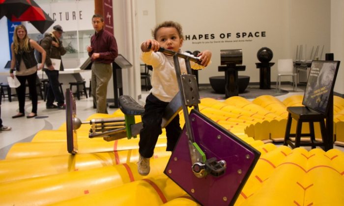 A little boy attempts to use a square-wheeled tricycle at the MoMath Museum in New York, Dec. 13. (Benjamin Chasteen/The Epoch Times)
