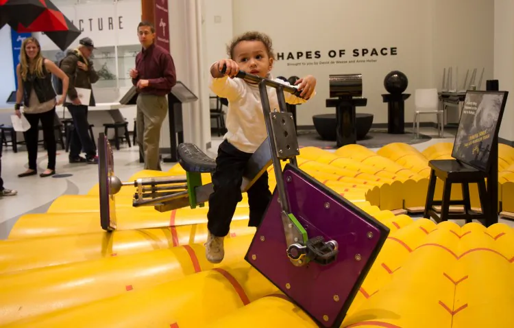 A little boy attempts to use a square-wheeled tricycle at the MoMath Museum in New York, Dec. 13. (Benjamin Chasteen/The Epoch Times)