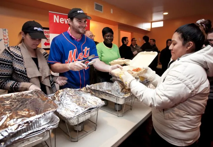 New York Mets professional baseball player Daniel Murphy and New York Cares volunteers distribute donated clothing, diapers, food, and water to residents of the Far Rockaway neighborhood of Queens affected by Hurricane Sandy; Community Church-The Nazarene, 1414 Central Ave., Queens on Jan. 16. (Samira Bouaou/The Epoch Times)