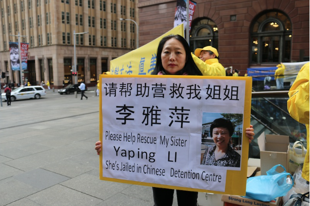 Mrs Ying Li holds a placard asking for the public's help to rescue her sister, Yaping Li, who was arrested five months ago for practising Falun Gong. (Melanie Sun/Epoch Times)