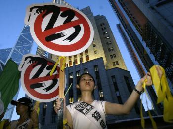 A girl hands out yellow ribbons against the controversial Article 23 law during a protest 09 July 2003. (Peter Parks/AFP/Getty Images)
