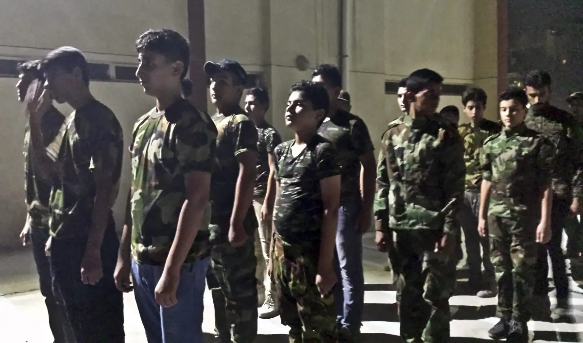 In this Tuesday, July 14, 2015 photo, Iraqi volunteers with Popular Mobilization Forces train at a volunteers center in Baghdad, Iraq. The Associated Press has found that militia forces battling the Islamic State group are actively training children under 18 years old. (AP Photo/Vivian Salama)