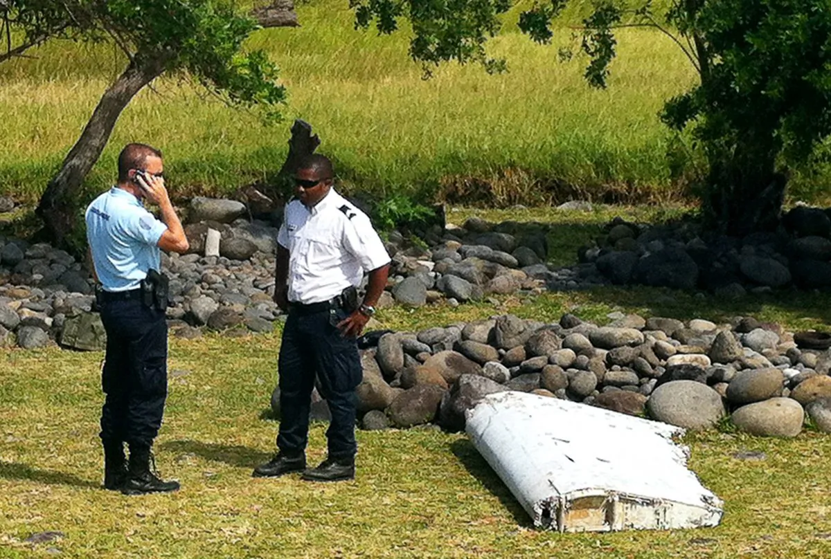 A policeman and a gendarme stand next to a piece of debris from an unidentified aircraft found in the coastal area of Saint-Andre de la Reunion, in the east of the French Indian Ocean island of La Reunion, on July 29, 2015. (Yannick Pitou/AFP/Getty Images)