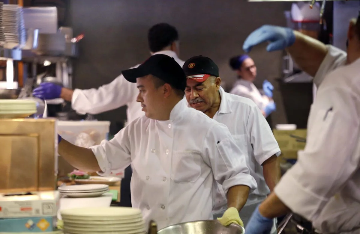 In this photo taken Monday, July 27, 2015, Arturo Ramirez, left, and other workers crowd the kitchen at an Ivar's restaurant in Seattle. (AP Photo/Elaine Thompson)