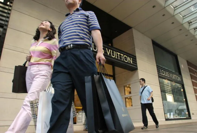 Mainland Chinese tourists loaded with shopping bags walk past a designer brand shop in the Tsim Sha Tsui area of Hong Kong (Getty Images)