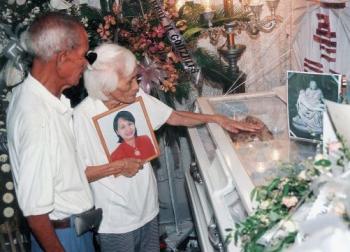 Pacencia Garcia holds a photograph of her slain daughter, Marlene Esperat, as she and her husband attend Esperat's funeral wake after she was killed in a brutal execution-style killing in the Philippines in 2005. (Mark Navales/AFP/Getty Images)