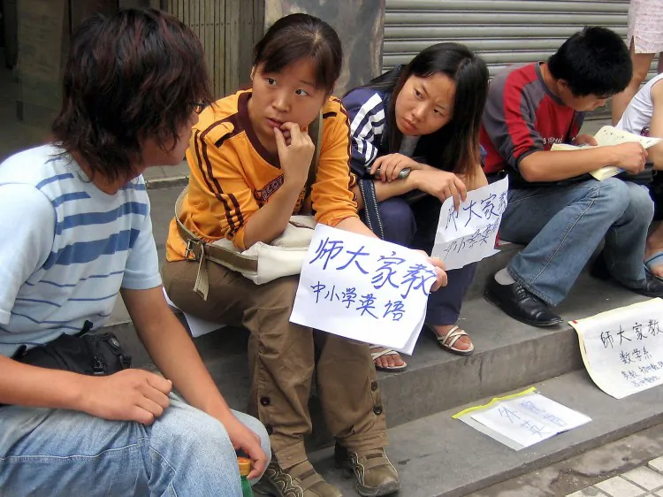 College students and graduates sit by a sidewalk offering their tutoring services, in Xi'an, central China's Shaanxi Province. Millions of college graduates in China are finding themselves with no jobs waiting, or end up performing work for which they are overqualified. (STR/AFP/Getty Images)