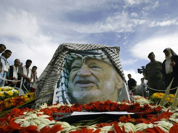 Palestinians pray on late Palestinian leader Yasser Arafat grave at the Mouqataa, his destroyed headquarters in the West Bank town of Ramallah 13 November 2004. (Awad Awad/AFP/Getty Images)