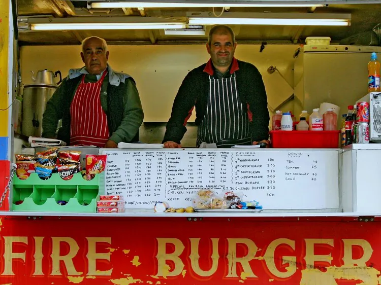 Father and son Ismayil (L) and Ersan Ibrahim work in their portable burger trailer in London, England on April 20, 2006. (Scott Barbour/Getty Images)