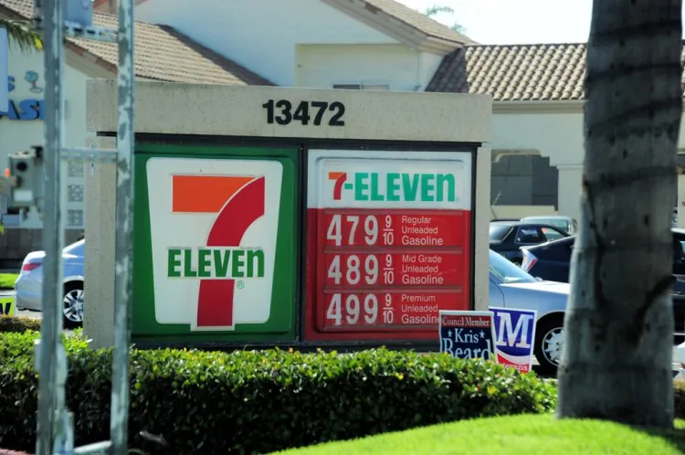 Man stands waiting for an Orange County Transportation Authority bus, oblivious to the high gasoline prices at the 7-Eleven convenience store behind him in Garden Grove, Calif. (Robin Kemker/The Epoch Times)