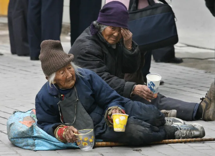 A pair of elderly Chinese women beg on a busy road in Shanghai, in December 2006. The number of elderly Chinese who have been abandoned as their children seek work in the cities is increasing. (Mark Ralston/AFP/Getty Images)