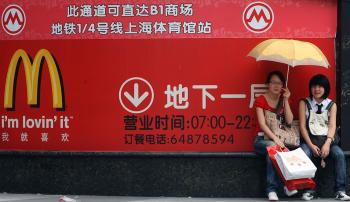 Two women site next to a huge McDonalds advertisement in Shanghai, in 2007. McDonald's Corp. said on Wednesday that it would open 200 new store locations in China to expand its operations in the world's most populous country. (Marcus Brandt/Getty Images )