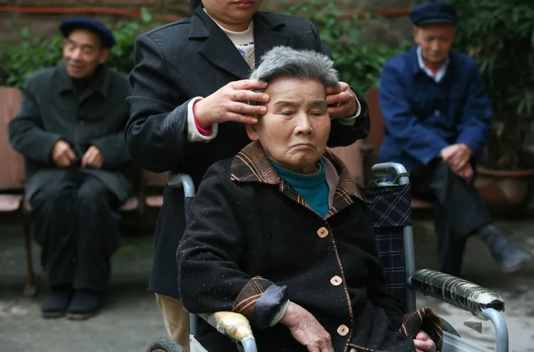 An attendant gives massage to a senior citizen in an elder care center on Oct. 16, 2007 in Chongqing, China. (China Photos/Getty Images)