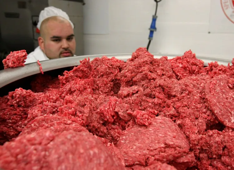 A pile of ground beef passes through a machine that makes hamburger patties at a meat packing and distribution facility June 24, 2008 in San Francisco, California. (Justin Sullivan/Getty Images)