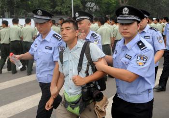 Chinese police detain a newspaper photographer Felix Wong from Hong Kong, who was photographing people waiting to buy the final batch of Olympic tickets, on sale near the Olympic Stadium in Beijing on July 25, 2008. (Mark Ralston/AFP/Getty Images)