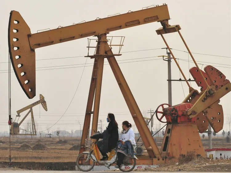 People sharing a scooter ride past oil rigs in Cangzhou on Feb. 25, 2009, in northern China's Hebei Province. Politically connected families control China’s major industries, with the oil industry dominated by the family of security czar Zhou Yongkang. (Frederic J. Bwown/AFP/Getty Images)