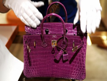 A woman inspects a Hermes crocodile skin bag. (Sam Yeh/AFP/Getty Images)