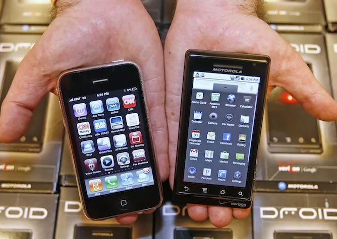 A manager of an electronics store holds an Apple iPhone (L) and a Motorola's Droid smart phone (R) in this 2009 file photo. Apple products could be banned from being sold in Germany due to possible violation of two Motorola patents. (George Frey/Getty Images)