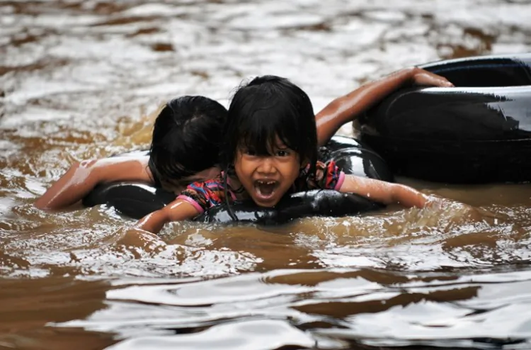 Children paddle with an inflatable ring through floodwaters in front of their houses in Jakarta, Indonesia on Feb. 18, 2010. A new bout of flood waters submerged Jakarta on Dec. 24, 2012, affecting so far 10,250 families. (Bay Ismoyo/AFP/Getty Images)