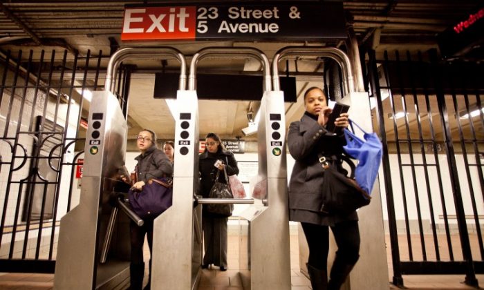 Commuters at the 23rd Street and Fifth Avenue station pass through turnstiles last winter. (Amal Chen/The Epoch Times)
