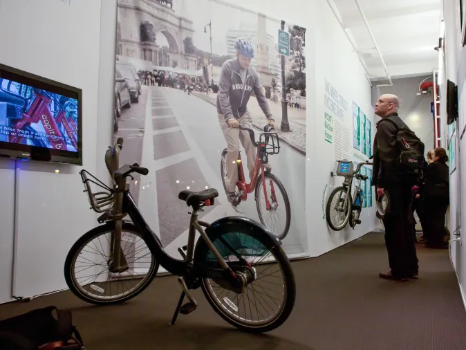 Alison Cohen, president of Alta Bicycle Share, speaks at the opening of the Center for Architecture's new bike share exhibit on Wednesday. Alta is the operator for New York's planned bike share, and also manages Washington, D.C's, system, seen in the slide in the background. (Amal Chen/The Epoch Times)