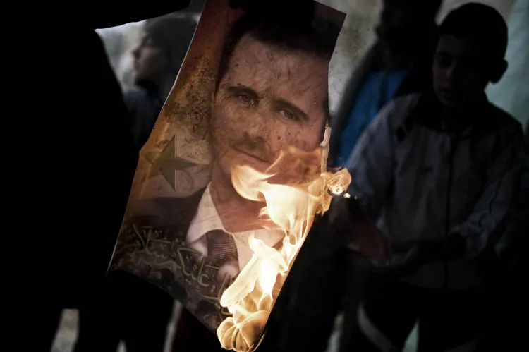 A member of the Free Syrian Army holds a burning portrait of President Bashar al-Assad in Al-Qsair, on Jan. 25, 2012. In a recent interview, Assad scorned foreign intervention in the nation's civil war. (Alessio Romenzi/AFP/Getty Images)