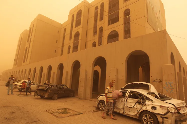 Iraqis inspect a car destroyed on Baghdad's Haifa Street, as dust creates a yellow haze, on April 19. A wave of car bombings and shootings in six different provinces across Iraq killed over 30 people, security officials said. (Ahmad Al-Rubaye/AFP/Getty Images)