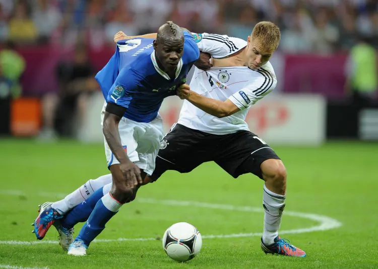Italy’s Mario Balotelli and Germany’s Holger Badstuber vie for the ball in Euro 2012 semifinal action on Thursday in Warsaw. (Christopher Lee/Getty Images)