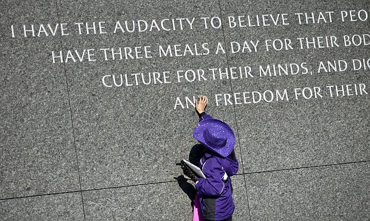 A young girl touches the quote at the Martin Luther King Jr. Memorial on the National Mall during a Martin Luther King Day wreath-laying ceremony, Jan. 15 in Washington. (Brendan Smialowski/Getty Image)