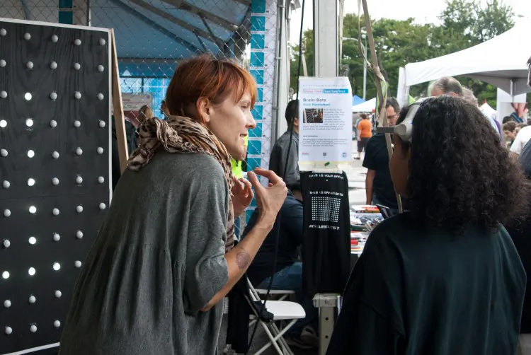A member of Hack Manhattan shows a passerby how to use the "Brain Bats" game of thought-controlled "Pong" at the World Maker Faire New York, held at the New York Hall of Science in Queens, on Sept. 29. (Joshua Philipp/The Epoch Times)