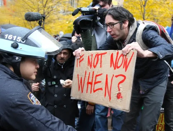Police officers closely watch the protesters as they march on Wall Street in New York on Thursday. (Benjamin Chasteen/The Epoch Times)