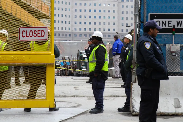 Construction workers and police officers stand in front of a truck that was crushed by metal beams as they fell from a crane when its cable snapped at 4 World Trade Center on Thursday. (Benjamin Chasteen/The Epoch Times)