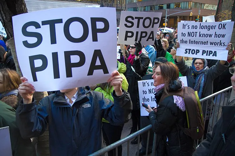 Demonstrators hold signs against proposed laws SOPA and PIPA, which will crack down on Internet piracy, in front of the Third Avenue offices of U.S. Sens. Chuck Schumer and Kirsten Gillibrand on Wednesday. (Benjamin Chasteen/The Epoch Times)