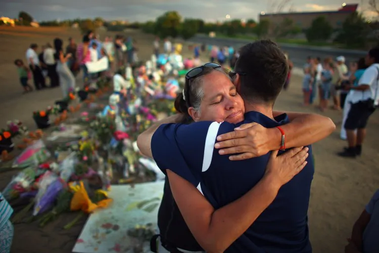 Julia Kouris hugs Steve Sundberg as they visit the memorial setup across the street from the Century Aurora 16 movie theater where a mass shooting took place on July 20, 2012, in Aurora, Co. Local officials said that the gunman used a rifle, a shotgun, and two Glock pistols, and that he was carrying 6,000 rounds of ammunition. (Joe Raedle/Getty Images)